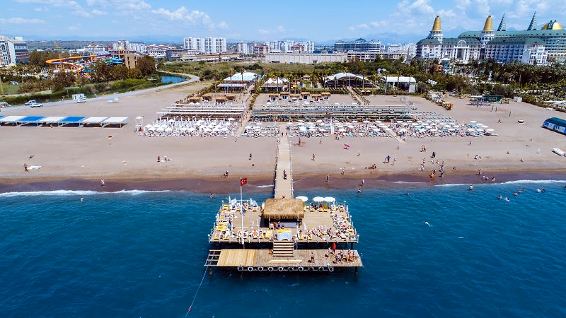 Luchtfoto van het strand met een pier, parasols en ligbedden aan de kust van Lara bij Wyndham Garden Lara