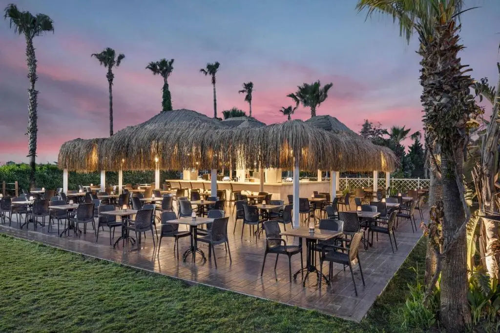 Verlicht restaurantterras met rieten parasols van Wyndham Garden Lara