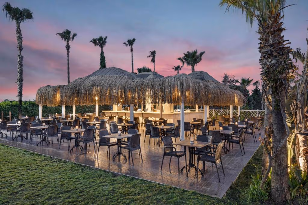 Verlicht restaurantterras met rieten parasols van Wyndham Garden Lara