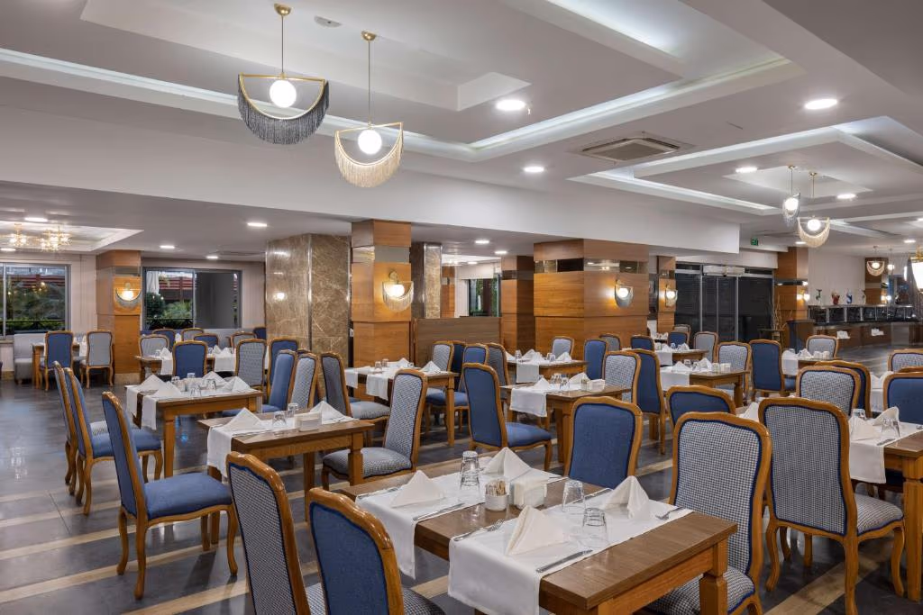 Restaurantzaal met houten tafels, blauwe stoelen met ruitpatroon en witte servetten bij Wyndham Garden Lara in Lara